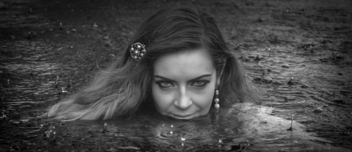 My favorite image of the series, rain droplets falling on the surface of the pool and those piercing eyes and mysterious smile. 
